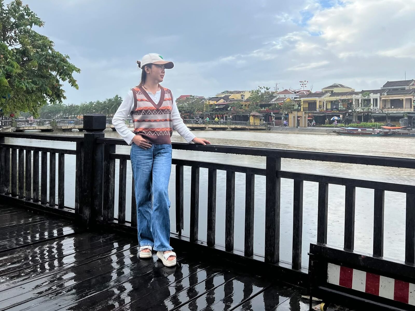 Phương on a bridge over the Thu Bồn river, with Hoi An's Old Town behind her